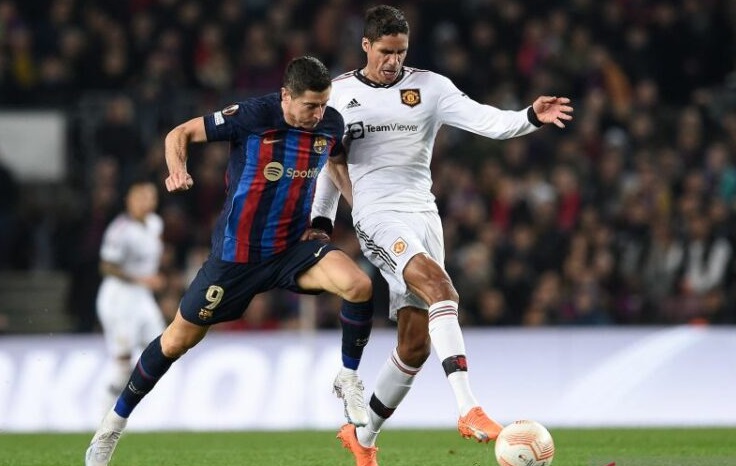 Panyerang Barcelona Robert Lewandowski (kiri) dikawal ketat bek Manchester United, Rapahael Varane pada leg kedua play-off Liga Europa di Old Trafford, Jumat (24/2/2023) dini hari WIB